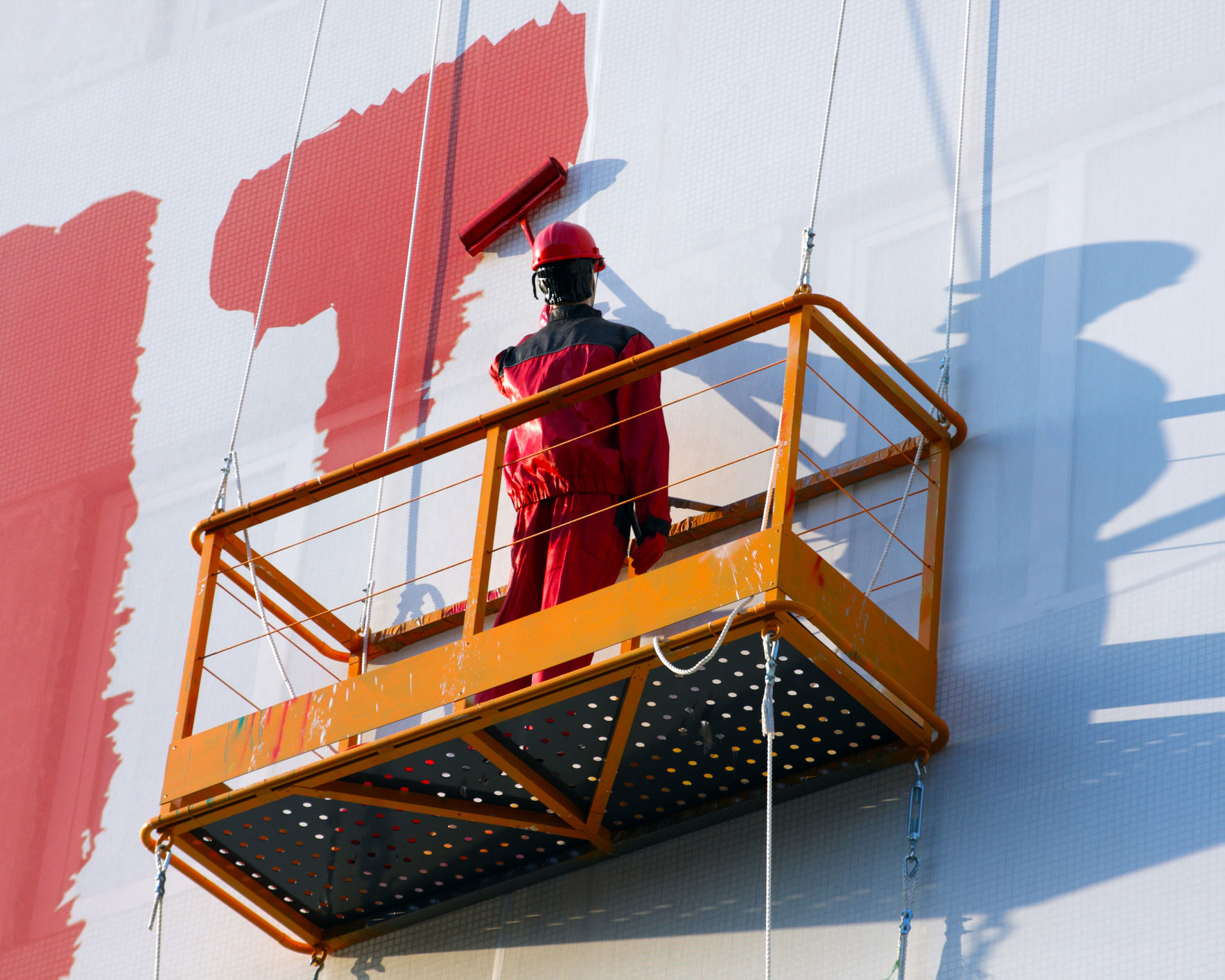 Painter on aerial platform painting large commercial building exterior