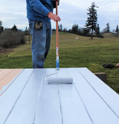 Painter rolling white waterproof coating onto a deck surface