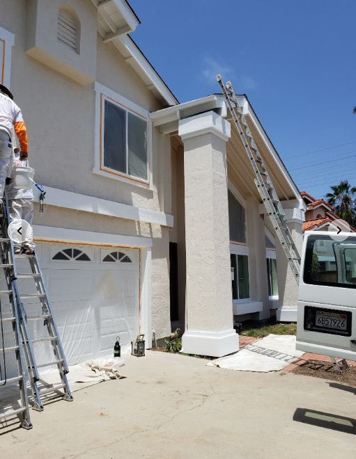 Painters on ladders repainting a two-story residential exterior